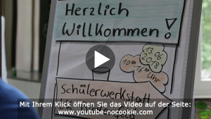 Das Bild zeigt einen Flipchart, auf dem "Herzlich Willkommen!" und "Schülerwerkstatt LK Birkenfeld" steht.