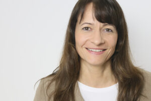Ein Bild mit Prof.‘in Dr.‘in Susanne Lang, sie lächelt freundlich in die Kamera, sie trägt lange Haar.