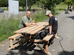 zwei Männer sitzen sich an einem Holztisch gegenüber.