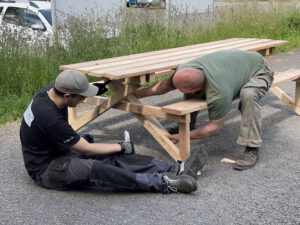 zwei Männer prüfen die Verbindungen an einem Holztisch