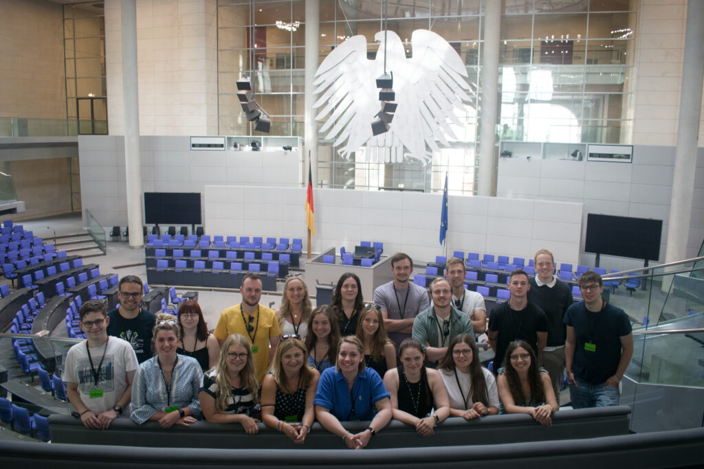 Ein Gruppenfoto des Jugendfonds auf der Besuchertribüne des Deutschen Bundestags. Im Hintergerund ist der Bundesadler zu sehen.