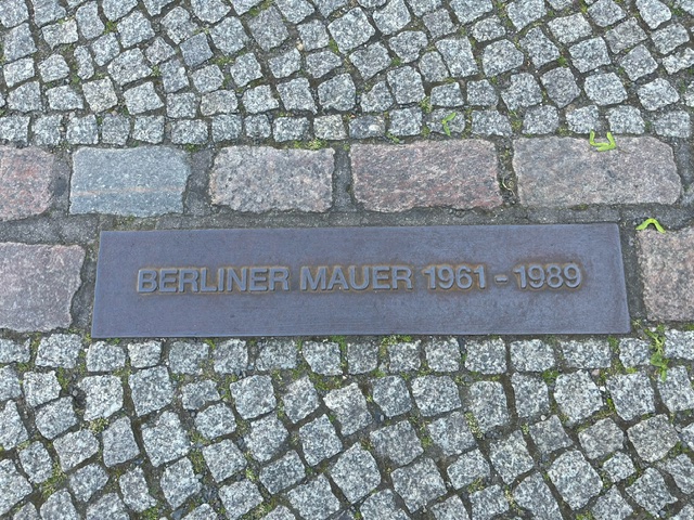 Eine im Boden eingelassene Eisenplatte, darauf steht: Berliner Mauer 1961-1989